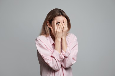 Young woman feeling fear on grey background