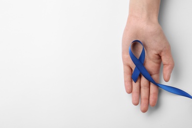 Woman holding blue awareness ribbon on white background, top view. Symbol of social and medical issues