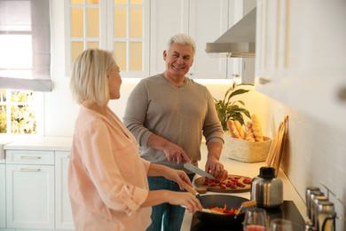 Mature couple cooking food together in kitchen