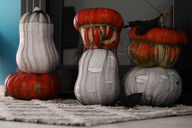 Colorful pumpkins on rug near fireplace. Halloween decorations