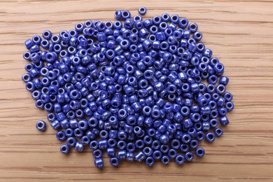 Pile of blue glass beads on wooden table, top view