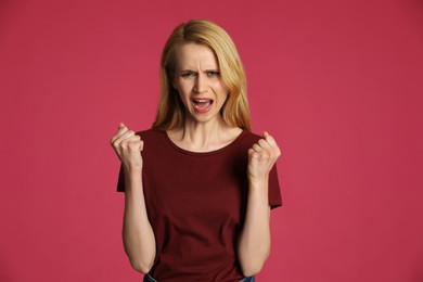 Angry young woman on pink background. Hate concept