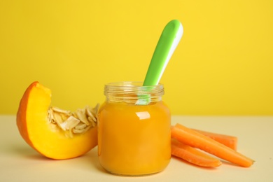 Healthy baby food and ingredients on table against yellow background