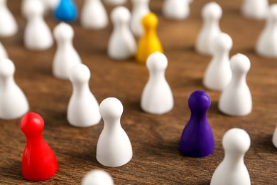 Photo of Colorful pawns on wooden table, closeup. Social inclusion concept