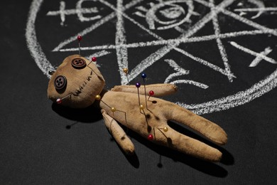 Voodoo doll near ritual circle drawn on black table