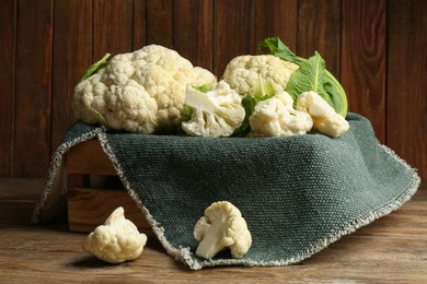 Photo of Crate with cut and whole cauliflowers on wooden table