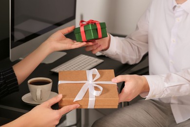 Photo of Colleagues presenting gifts each other in office, closeup