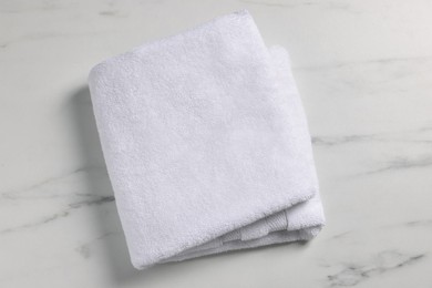 Photo of Clean folded towel on white marble table, top view