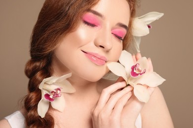 Photo of Portrait of beautiful happy woman posing with lilies on beige background, closeup