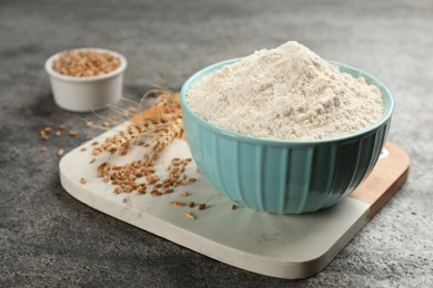 Bowl of flour and wheat kernels on grey table