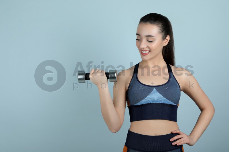 Photo of Woman with dumbbell as girl power symbol on light grey background, space for text. 8 March concept