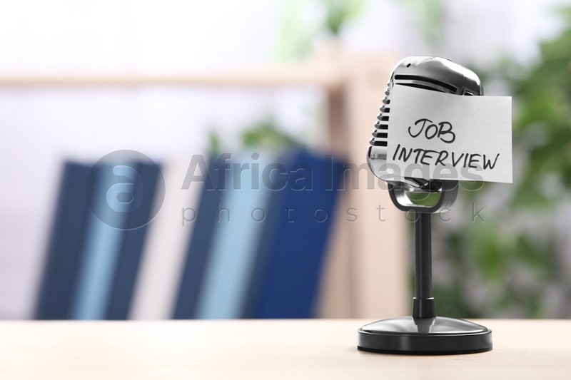 Photo of Retro microphone and reminder note with words JOB INTERVIEW on table indoors, space for text