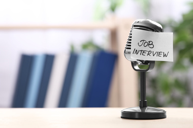 Retro microphone and reminder note with words JOB INTERVIEW on table indoors, space for text
