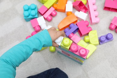 Top view of little child playing with building blocks on carpet, closeup