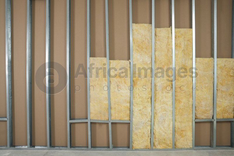 Wall with metal studs and insulation material indoors, space for text