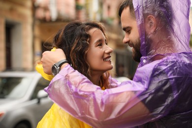 Young couple in raincoats enjoying time together on city street