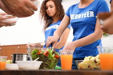Volunteers serving food to poor people in charity centre