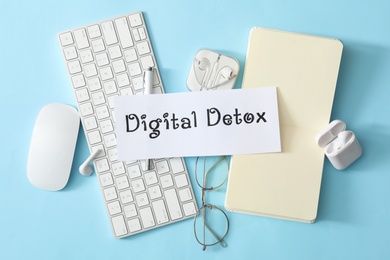 Photo of Flat lay composition of paper note with phrase DIGITAL DETOX on light blue background