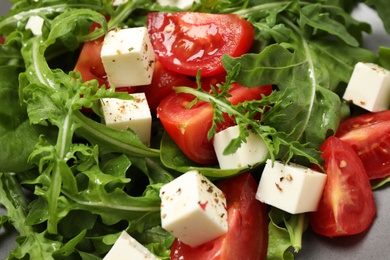 Delicious salad with feta cheese, arugula and tomatoes on plate, closeup