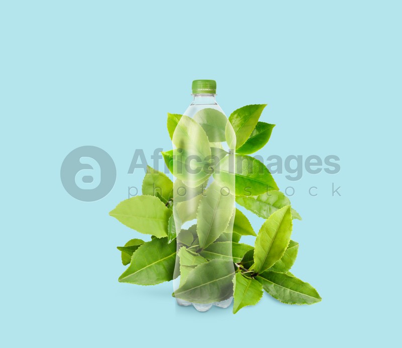 Bottle made of biodegradable plastic and green leaves on light blue background