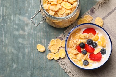 Photo of Delicious crispy cornflakes with milk and fresh berries on light blue wooden table, flat lay. Space for text