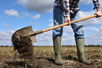 Man digging soil with shovel in field, closeup