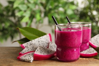 Delicious pitahaya smoothie and fresh fruits on wooden table, space for text