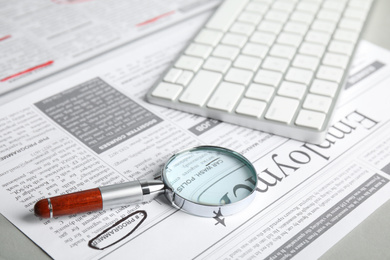 Magnifying glass and keyboard on newspaper. Job search concept