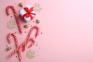 Flat lay composition with candy canes and Christmas decor on pink background. Space for text