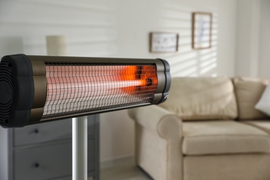 Modern electric infrared heater in living room, closeup