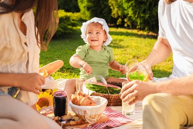 Cute child and her parents having picnic on sunny day in garden