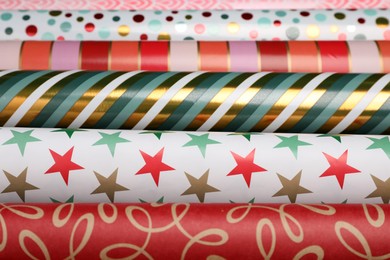 Different colorful wrapping paper rolls as background, closeup