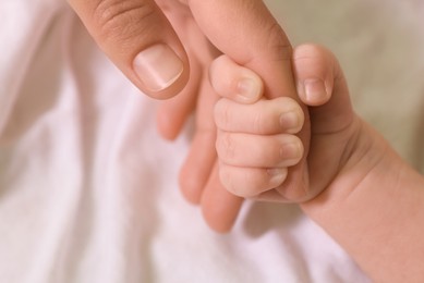 Mother and her newborn baby on bed, closeup of hands