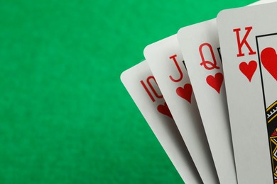 Photo of Hand of playing cards on green background, closeup. Space for text