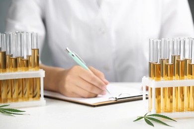 Test tubes with urine samples, hemp leaves and blurred doctor on background