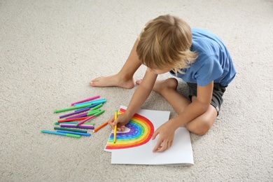 Little boy drawing rainbow on floor indoors. Stay at home concept