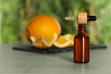 Photo of Bottle of citrus essential oil and pipette on grey table, space for text