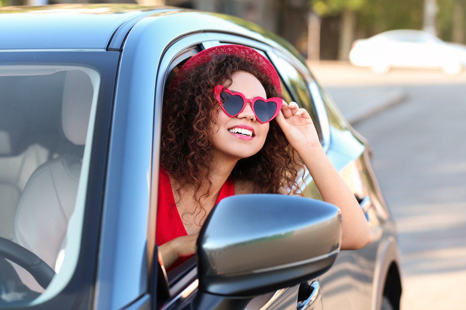 Young beautiful African-American woman wearing heart shaped glasses in car