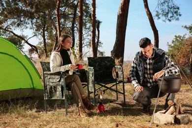Photo of Couple resting near bonfire at camping site