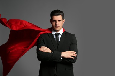 Businessman wearing superhero cape on grey background
