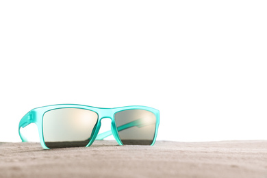 Stylish sunglasses on sand against white background. Space for text