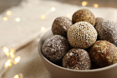 Different delicious vegan candy balls in bowl, closeup. Space for text