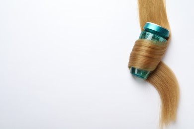 Photo of Bottle wrapped in lock of hair on white background, top view with space for text. Natural cosmetic product