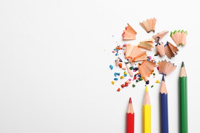 Photo of Color pencils, wooden shavings and crumbs on white background, top view