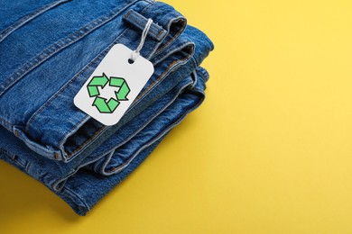Jeans with recycling label on yellow background. Space for text