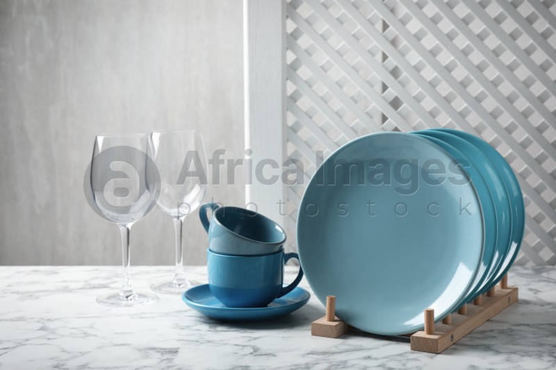 Photo of Set of clean dishware and glasses on white marble table