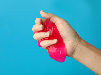 Woman playing with pink slime on light blue background, closeup. Antistress toy