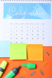 Calendar page and office stationery on orange background, flat lay