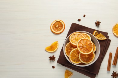 Photo of Many dry orange slices and spices on white wooden table, flat lay. Space for text