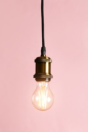Hanging modern lamp bulb against pink background